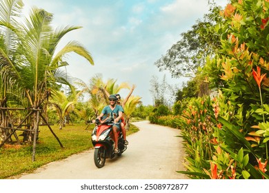 Happy smiling couple travelers riding motorbike scooter in safety helmets during tropical vacation under palm trees on Phu Quoc island ,Vietnam - Powered by Shutterstock