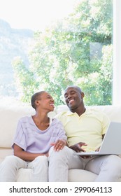 Happy smiling couple using laptop on couch in living room - Shutterstock ID 299064113