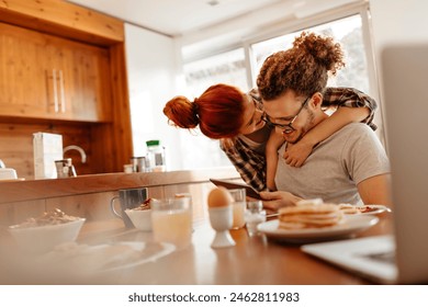 Happy smiling couple using tablet together at kitchen table - Powered by Shutterstock