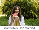 Happy smiling curly brunette woman eating watermelon in the park