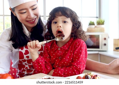 Happy Smiling Cute Little Girl Eating Chocolate And Face Covered In Chocolate, Adorable Child Daughter Enjoy Spending Time Together With Beautiful Young Mother. Love Warmth Family Mom And Kid Concept.