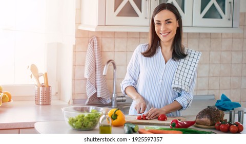 Happy Smiling Cute Woman Is Preparing A Fresh Healthy Vegan Salad With Many Vegetables In The Kitchen At Home And Trying A New Recipe