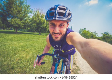 Happy Smiling Cyclist Man Driving A Bike Taking Selfie Photo, Cheerful Young Male Cyclist  In A Sunny Blue Sky Morning In The Green Forest, Workout, Healthy, Sport Lifestyle