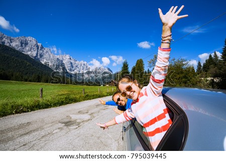 happy smiling dad and daughter looking out the car window and mountains in the background. Dolomites, Italy

