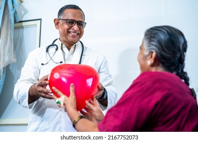 Happy Smiling Doctor Giving Balloon Heart To Recovered Senior Patient At Hospital - Concept Of Happiness, Cure And Positive Emotion.