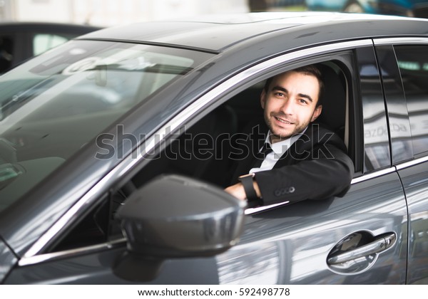 happy smiling driver in the car,\
portrait of young successful business man over window of\
car