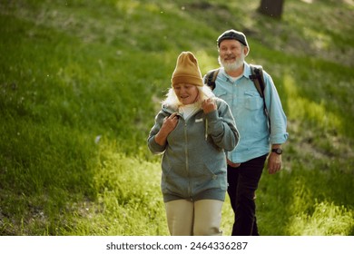 Happy, smiling elderly couple, man and woman holding hands, walk through park on warm sunny day. Hiking activity. Concept of sport, aging, active and healthy lifestyle, health care - Powered by Shutterstock