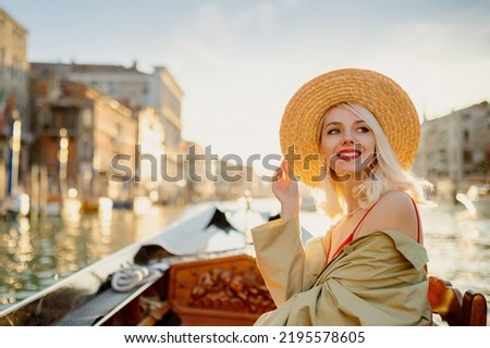 Happy smiling elegant woman wearing straw hat on Gondola ride during sunset, along the Grand Canal in Venice, Italy. Travel, vacation, lifestyle conception. Copy, empty space for text