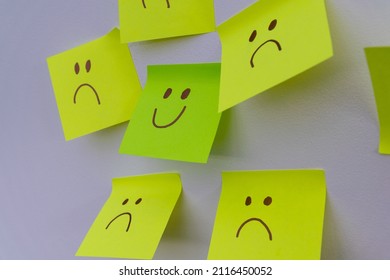 Happy Smiling Face Amongst Lots Of Sad Faces. Hiding Depression, Mental Health Issues Or Anxiety Concept. Two Faces Concepts Background. Pretending Faking It.