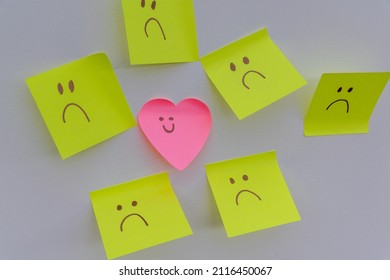 Happy Smiling Face Amongst Lots Of Sad Faces. Hiding Depression, Mental Health Issues Or Anxiety Concept. Two Faces Concepts Background. Pretending Faking It.