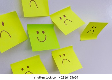 Happy Smiling Face Amongst Lots Of Sad Faces. Hiding Depression, Mental Health Issues Or Anxiety Concept. Two Faces Concepts Background. Pretending Faking It.