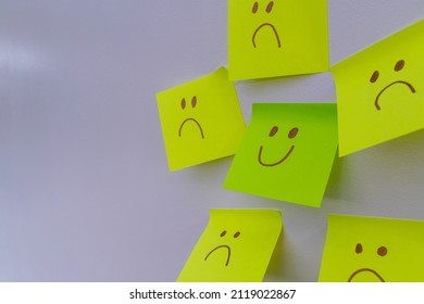 Happy Smiling Face Amongst Lots Of Sad Faces. Hiding Depression, Mental Health Issues Or Anxiety Concept. Two Faces Concepts Background. Pretending Faking It.