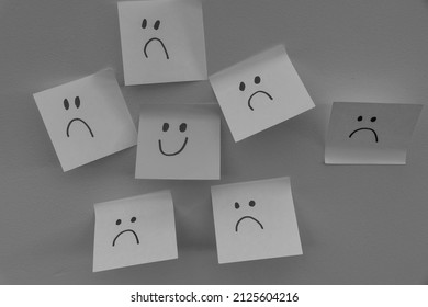 Happy Smiling Face Amongst Lots Of Sad Faces. Hiding Depression, Mental Health Issues Or Anxiety Concept. Two Faces Concepts Background. Pretending Faking It.