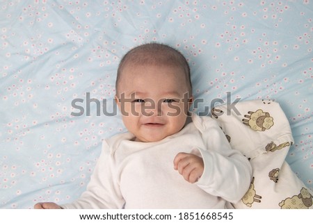 Happy Smiling face Asian Chinese baby boy during lying on bed. Happy Newborn child relaxing in bed