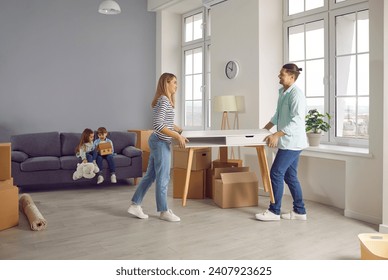 Happy smiling family couple with two kids boy and girl on background arranging furniture in a new apartment on moving day with unpacked boxes. Relocating, real estate, mortgage concept.