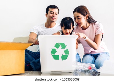 Happy smiling family having fun putting empty recycling plastic bottles and paper into the recycle box - Powered by Shutterstock