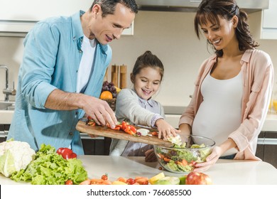 Happy Smiling Family Making Salad Together At Kitchen 