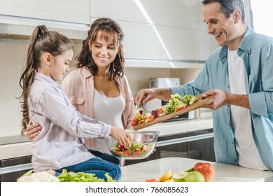 Happy Smiling Family Making Salad Together At Kitchen 