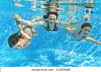 Happy Smiling Family Underwater In Swimming Pool. Mother And Children Swim And Having Fun. Kids Sport On Family Summer Vacation. Active Healthy Holiday