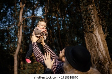 Happy smiling family is walking autumn in the park. Father, mother and  6 month old baby girl are playing in a fall park.  - Shutterstock ID 1910818870