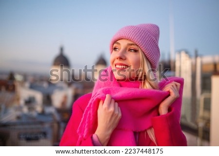 Happy smiling fashionable woman wearing trendy total pink outfit with knitted beanie hat, woolen scarf, coat, posing outdoor. Copy, empty space for text