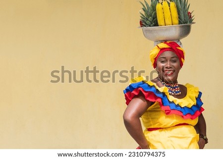 Happy, smiling fresh fruit street vendor aka Palenquera in the Old Town of Cartagena, Colombia. Cheerful Afro-Colombian woman in traditional clothing, Colombian culture and lifestyle. 