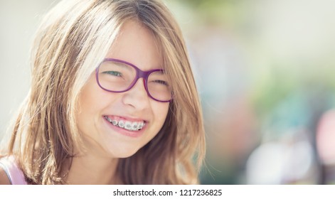 Happy smiling girl with dental braces and glasses. Young cute caucasian blond girl wearing teeth braces and glasses. - Shutterstock ID 1217236825
