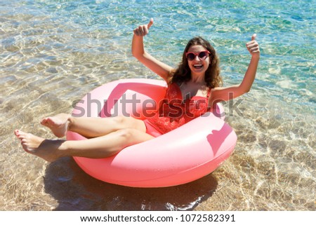 Happy Smiling girl enjoys floating on inflatable donut in sea. vacation time.