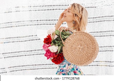 Happy Smiling Girl Holding Round Wicker Straw Bag With Peonies. Model Wearing Summer Dressing Gown With Colorful Flower Print. Copy, Empty Space For Text