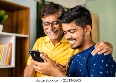 Happy Smiling Grandson Showing New Application On Mobile Phone To Grandfather At Home - Concept Of Social Media, Surfing Internet And Cyberspace