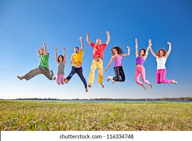 Happy smiling  group of jumping  people on banch of lake