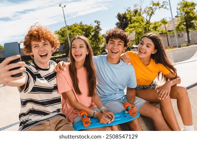 Happy smiling group of teenagers high school pupils friends classmates college students boys girls with bags hanging out take selfie shot picture photo having fun in skate park sitting on ramp outside - Powered by Shutterstock