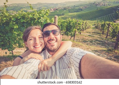 happy smiling handsome couple visiting vineyard area and taking photo selfie for wine tasting tour in Roero Monferrato Langhe Barolo town. vintage colors photo - Powered by Shutterstock