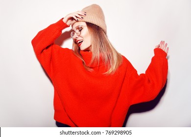 Happy Smiling Hipster Girl In Knitted Red Sweater And Hat Having Fun . Cute Girl In Glusses With Piercing In The Nose. Winter Or Autumn Warming Up Concept. Dance. Fashion.