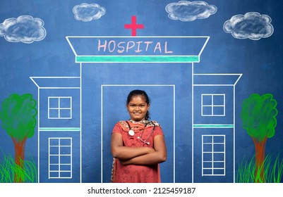 Happy Smiling Indian Girl Kid With Stethoscope Standing Infront Of Hospital Painting - Concept Of Poor Child Dreaming About Doctor As Future Career And Education.