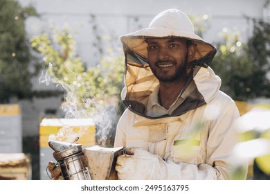 Happy smiling Indian male Beekeeper smoking honey bees with bee smoker on the apiary - Powered by Shutterstock