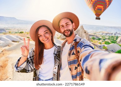 Happy smiling joyful traveling couple takes selfie photo in Nevsehir, Goreme. Beautiful destination with colorful flying hot air balloons in Anatolia, Kapadokya - Powered by Shutterstock