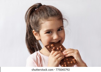 Happy smiling kid girl biting tasty chocolate with empty copy space. Isolated portrait