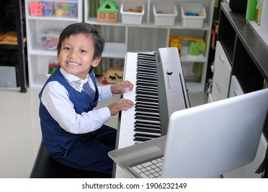 Happy Smiling Kid Studying Piano Music Lesson Online With Laptop Computer. Homeschool And Distance Learning Concept.