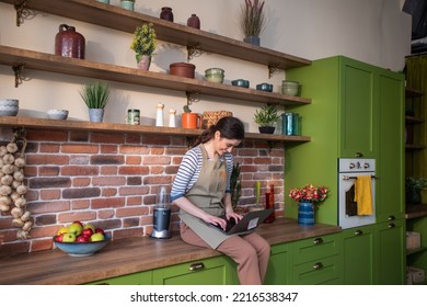 Happy And Smiling Large Woman Working On Her Laptop While Sitting Over The Kitchen Table In The Large Kitchen She Looking At The Window And Smile Large