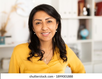 Happy smiling Latin American businesswoman standing in office and looking at camera