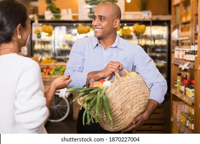 Happy Smiling Latino Standing With Purchases In Grocery Store, Friendly Talking To Woman