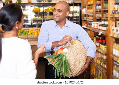 Happy Smiling Latino Standing With Purchases In Grocery Store, Friendly Talking To Woman