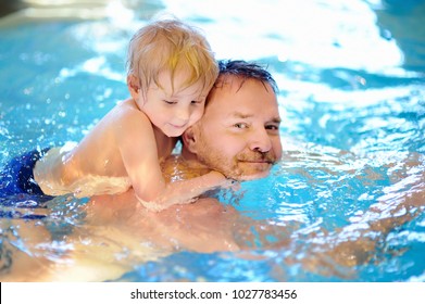 Happy Smiling Little Boy With His Father In Swimming Pool. Cute Child Swims And Having Fun. Kids Sport On Family Summer Vacation. Active Healthy Holiday