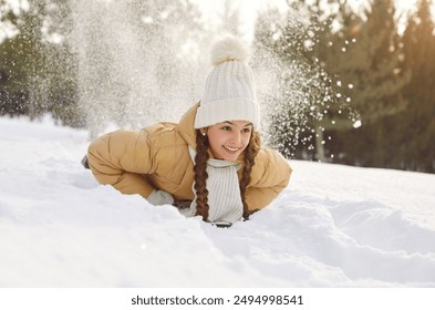 Happy smiling little child girl riding on a snow slide in winter park. Joyful kid having fun in nature sliding down in snowy weather outdoor. Winter activities and holiday concept. - Powered by Shutterstock