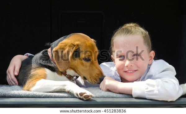 Happy smiling\
little girl and beagle puppy in\
car