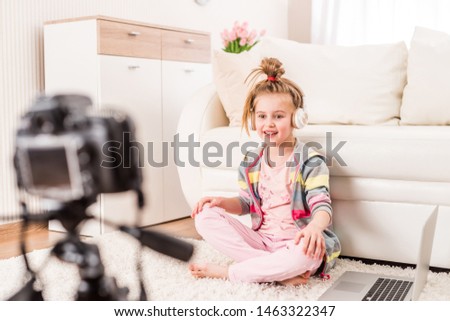 Happy smiling little girl recording video with headphones on