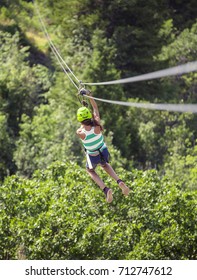 Happy Smiling Little Girl Riding A Zip Line In A Lush  Forest While On Family Vacation