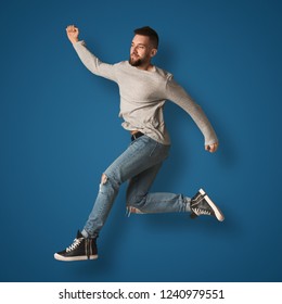 Happy Smiling Man Jumping. Fashion Boy At Blue Background, Studio Shot