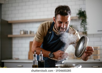 Happy smiling man preparing tasty meal. Young man cooking in the kitchen. - Powered by Shutterstock